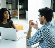 two diverse business people sitting opposite each other having a meeting